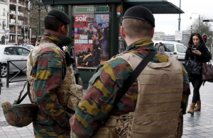 Belgian soldiers stand guard in front of a poster for Le Soir (The Evening) weekly news magazine showing a photograph of the Paris attack that reads, "We are at war", after security was tightened following the fatal attacks in Paris, in Brussels, Belgium, November 21, 2015. REUTERS/Francois Lenoir - RTX1V4NT